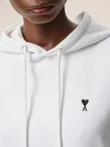 Buzo blanco con capucha y bolsillo tipo canguro, con logo bordado en el pecho.