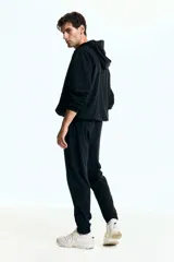 Jogging deportivo negro de corte estándar, confeccionado en punto funcional con tecnología DryMove™ que absorbe el sudor. Presenta cintura elástica con cordón de ajuste, bolsillos al bies con cierre y bajos ajustados con cierre y elástico.