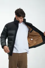 Campera puffer negra y beige con cierre frontal y cuello alto. Estampado con la marca "Unfrm" en el pecho.