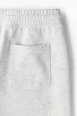 Pantalon deportivo de felpa gris claro melange, de corte relajado, con cintura elastizada y cordon de ajuste, bolsillos laterales y punos acanalados.