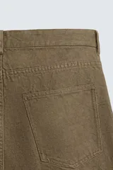 Pantalón de algodón color verde oliva, de corte recto (regular fit), con tiro medio, cierre frontal de cremallera y botón, y cinco bolsillos.