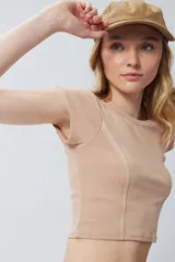 Top corto de manga corta, color negro con efecto desgastado o acid wash, cuello redondo y costuras verticales que definen la silueta.