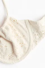 Top de bikini balconette con aros y textura perforada, tirantes finos ajustables y lazada frontal.
