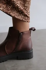 Bota corta de cuero color marrón con suela track dentada y cierre lateral.
