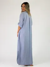 Vestido largo de lino marrón con cierre frontal de botones, cuello camisero, mangas tres cuartos con presilla y costuras decorativas blancas en la botonera.