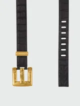 Cinturón Balmain modelo Anthem confeccionado en cuero negro con textura de cocodrilo. Presenta una hebilla cuadrada grande de metal en tono dorado envejecido con el logo grabado y una trabilla metálica a juego.
