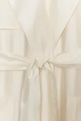 Chaleco largo fluido confeccionado en mezcla de lyocell, color crudo, con cuello de solapa, manga sisa, bolsillos frontales de plastrón y cinturón ajustable del mismo tejido.