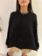 Sweater tejido color negro, con cuello redondo y diseño de ochos en el frente y mangas con diseño a rayas verticales.