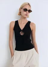 Top sin mangas de tejido de punto fino, con cuello en pico y detalle de lazo frontal en el escote. Presenta un diseño entallado con tirantes anchos.