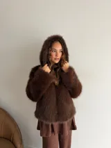 Campera de piel sintética en color marrón, con diseño de corte recto, mangas largas y capucha integrada.