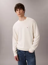 Sweater Calvin Klein de tejido de punto color blanco marfil, con cuello redondo, puños y bajo acanalados, y pequeño monograma CK bordado en el pecho.