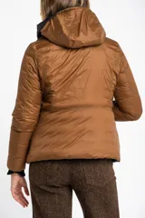 Campera reversible con diseño acolchado, cierre frontal y capucha. Un lado es de color negro y el otro de color tostado, con puños tejidos en color negro.