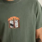 Remera de algodón verde militar con efecto vintage, de manga corta y cuello redondo. Presenta un pequeño estampado frontal en el centro con la inscripción 'Rhythm' y un diseño gráfico.