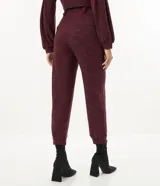 Pantalón jogger color borgoña confeccionado en malla flamê texturizada, con cintura con trabillas largos, cordón para amarre, pliegues delanteros y barra ajustada con pliegues.