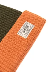 Gorro de lana tejido a punto, color verde oliva en la parte superior y naranja en el borde inferior. Tiene una etiqueta rectangular cosida en el frente con el logo de la marca Denali.