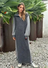 Vestido largo de punto en combinación de tonos grises, con cuello polo y cierre frontal parcial. Presenta mangas largas con detalle de perforaciones y aberturas laterales en el ruedo.