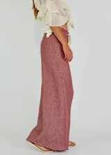 Pantalón de lino color ladrillo, de corte palazzo y tiro alto, con bolsillos laterales y cordón ajustable en la cintura.