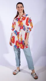 Camisa blanca de manga larga con estampado abstracto en colores rojo, naranja y azul. Tiene cuello clásico y cierre frontal de botones.