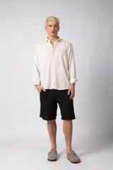 Camisa de manga larga con cuello clásico y cierre frontal de botones. Presenta un calce relajado y una textura liviana.