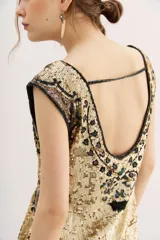 Vestido corto de lentejuelas doradas con diseño estampado de corazones y motivos ornamentales en tonos oscuros. Presenta un corte recto y sin mangas.