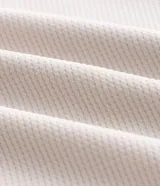 Bermuda deportiva Get Over de color beige, confeccionada en poliéster con textura en relieve. Cuenta con cintura elástica con cordón ajustable, bolsillos laterales con cierre e insignia estampada en la pierna.