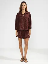 Camisa de manga larga color rosa con rayas verticales rojas y estampado de flores rojas. Con cuello camisero, puños elastizados y lazos regulables en los costados del ruedo.