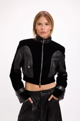 Campera crop de paño negro con recortes en cuero sintético, cuello alto con hebilla metálica, cierre frontal y hombreras marcadas.