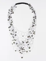 Collar de cuentas azules y celestes con hilos plateados y cierre de cordón negro.