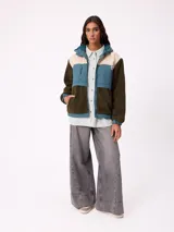 Campera con capucha de diseño combinado en bloques de color. Presenta una sección superior en pana rosada, una franja central en nylon marrón con logo de la marca y cuerpo inferior y mangas en tejido sherpa color crema. Incluye cierre frontal y bolsillos laterales.