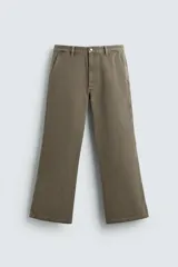 Pantalón de denim color verde oliva, estilo chino con corte ancho y bota acampanada (flare) desde la rodilla. Tiro medio, confeccionado en tejido rígido. Presenta bolsillos frontales y bolsillos traseros de plastrón.