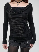 Remera manga larga de corte slim fit en color negro, confeccionada en poliéster con estampado por sublimación en el frente. Presenta escote redondo amplio con detalle drapeado y tachas metálicas aplicadas en el borde.