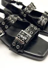 Sandalias planas color verde oliva, con punta cuadrada, dos tiras anchas sobre el empeine con hebillas metálicas y pulsera al tobillo con hebilla.