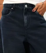 Pantalón barrel de jean color azul oscuro con lavado desgastado, de cintura alta, corte amplio en las piernas y botamanga afinada. Cuenta con cierre frontal y bolsillos funcionales.