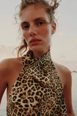 Top halter satinado con estampado de leopardo, cuello desbocado y espalda descubierta con cierre de botón en la nuca.