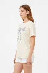 Remera blanca de manga corta y cuello redondo, confeccionada en algodón, con un diseño holgado y estampado frontal de estrella roja con textura y detalles de estrellas pequeñas.
