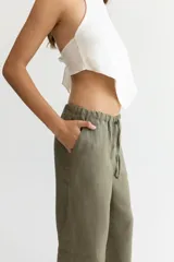 Pantalón color beige de lino, con elástico y tira ajustable en la cintura, bolsillos a ambos lados y pata de elefante estilo Oxford.