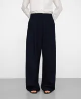 Pantalón de tiro alto, corte barrel y diseño ancho, color azul marino, con trabillas en la cintura, pliegues frontales y bolsillos laterales.
