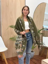 Bufanda rectangular con estampado a cuadros en tonos beige, azul y verde. Tiene flecos en los extremos y un estampado floral en el interior.