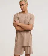Pijama corto de hombre confeccionado en malla flameada de color gris con efecto mezcla, compuesto por una remera de manga corta con cuello redondo y un short con cintura elástica.