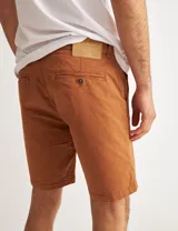 Bermuda color marrón de gabardina, corte chino, con bolsillos traseros tipo ojal con botón.