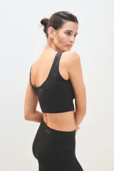 Top deportivo de escote redondo y espalda estilo nadadora, confeccionado en tejido técnico elástico. Presenta un diseño minimalista con logo sutilmente estampado en la parte posterior.