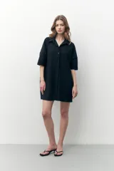 Vestido camisero negro con textura plisada, corte midi y cierre frontal con botones.