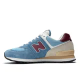 Championes urbanos New Balance modelo 574, con diseño híbrido para asfalto y trail. Presentan una combinación de tonos celestes, azules, beige y detalles en bordó, confeccionados en gamuza y malla, con el logotipo "N" característico en los laterales y entresuela ENCAP.