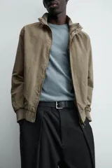 Cazadora azul marino de corte regular fit, confeccionada en tejido técnico repelente al agua. Presenta cuello subido, manga larga, bolsillos de vivo en cadera, bolsillo interior y acabados en rib en puños y bajo. Cierre frontal de cremallera oculta por solapa con botones a presión.