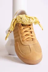 Zapatillas bajas color marrón con cordones y charms dorados.