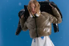Campera puffer corta a la cintura, color verde militar con acabado brillante. Presenta cuello alto, cierre frontal completo y bolsillos laterales con cierre invisible.