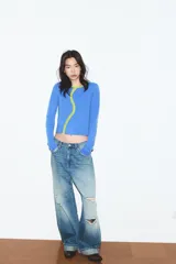 Chaqueta de punto color azul, con cuello redondo y manga larga. Presenta acabados en contraste de color verde neón y cierre frontal cruzado con botones.