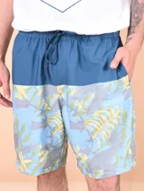 Bermuda de baño celeste con estampado de hojas amarillas y grises, y cintura azul petróleo con cordón ajustable.