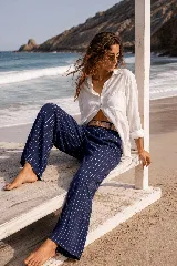 Pantalón de lino azul marino con finas rayas verticales blancas, de corte amplio y talle alto. Incluye bolsillos funcionales y una cintura elástica con cinturón de rafia desmontable.