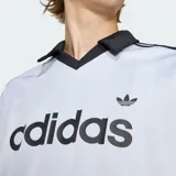 Camiseta deportiva Adidas de manga corta, color celeste con sutiles rayas verticales, cuello polo negro en V y las clásicas tres tiras negras en los hombros. Cuenta con el logotipo de la marca y la inscripción "adidas" en el pecho en color negro.